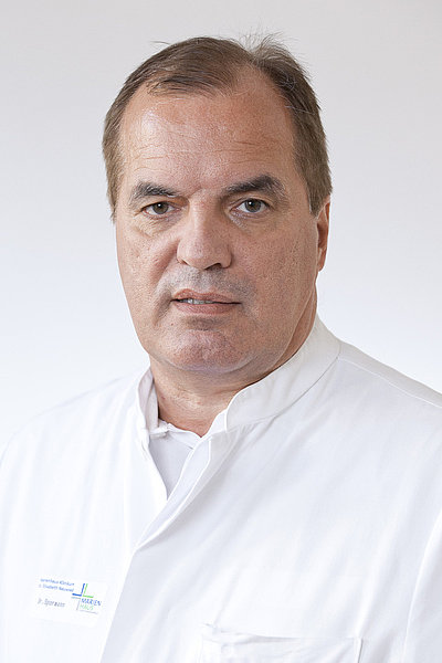 Dr. Spormann, Oberarzt und Facharzt für Allgemein-, Visceral- und Gefäßchirurgie, in weißem Arztkittel vor hellem Hintergrund