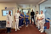 Gruppe von medizinischem Personal und zwei weiteren Personen steht in einem Krankenhausflur