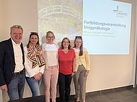 Fünf Personen stehen nebeneinander vor einer Wand mit einem Projektionsbild zur Fortbildungsveranstaltung Urogynäkologie im Marienhaus.