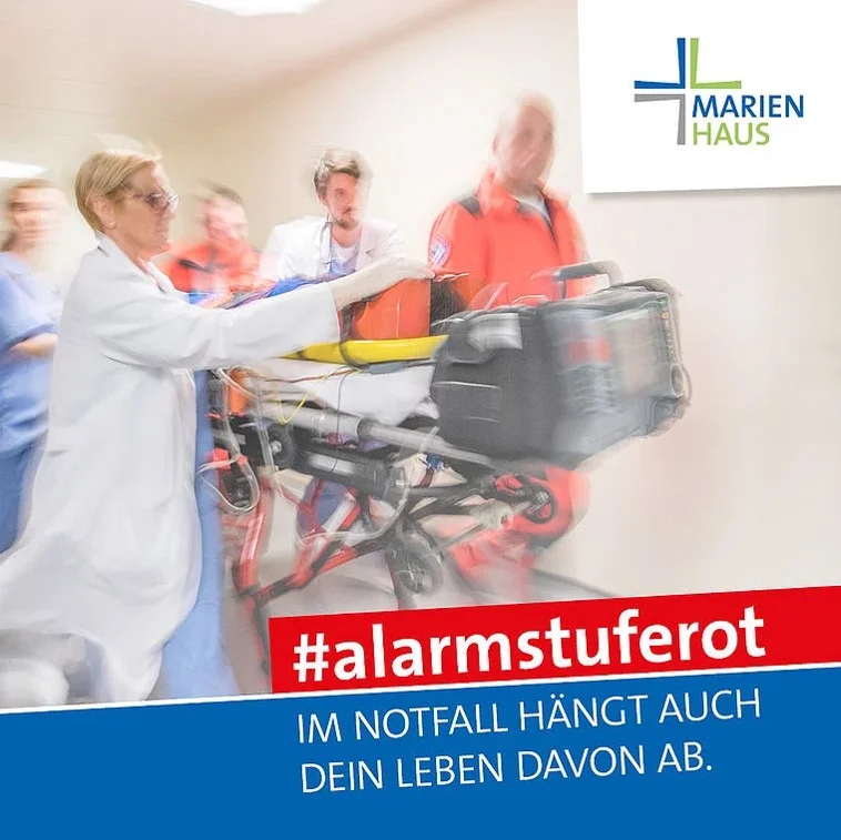 Medizinisches Personal schiebt eine Trage mit Notfallausrüstung im Krankenhaus Marien Haus, Text: '#alarmstuferot Im Notfall hängt auch dein Leben davon ab'.