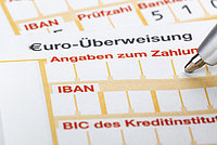 Ausschnitt eines SEPA-Überweisungsformulars mit sichtbaren Feldern für IBAN, BIC und Angaben zum Zahlungsempfänger; eine Stiftspitze zeigt auf das Formular. 