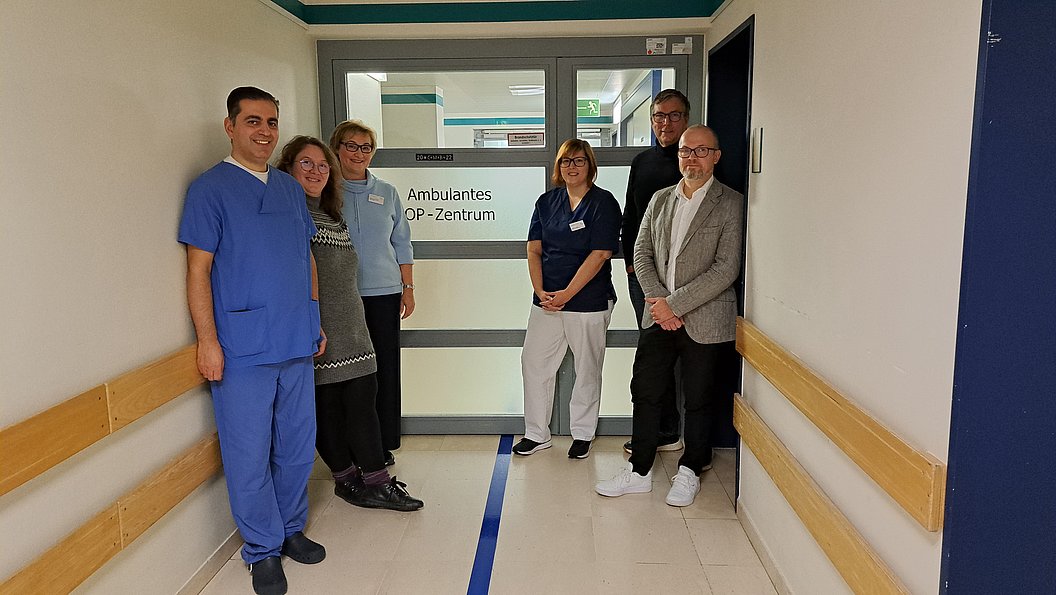 Fünf Personen stehen im Flur vor der Tür zum ambulanten OP-Zentrum des Marienhaus Klinikum Eifel.