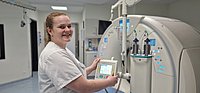 Eine Person in einem weißen Kittel bedient ein medizinisches Gerät mit einem Touchscreen. Das Gerät hat mehrere Zylinder und leuchtet blau.