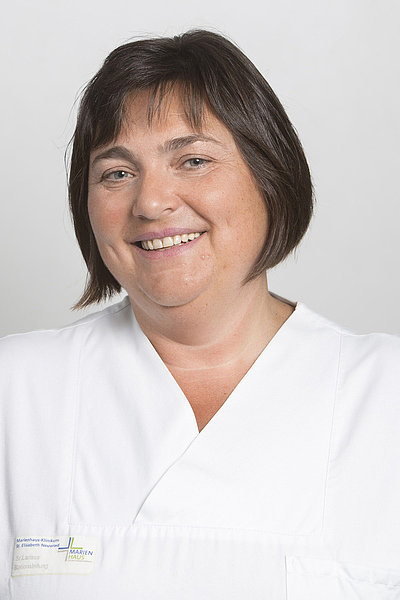 Larissa Glasomizki in weißer medizinischer Kleidung, Leitung Station 51 Gefäßchirurgie, lächelnd vor hellem Hintergrund